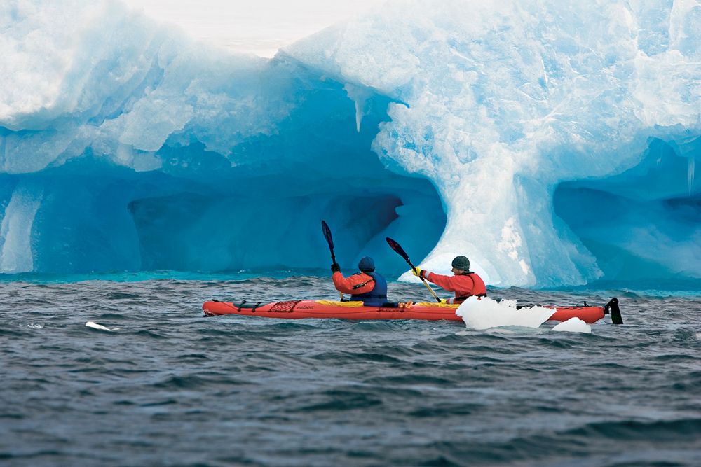 Sea kayaker paddling between icebergs in Antarctica